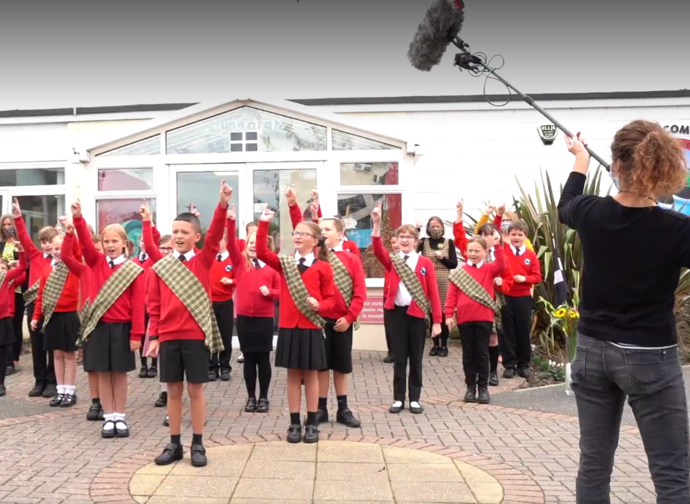 Treloweth Primary School Pupils Singing outside the School, wearing the uniform and Cornish tartan sashes