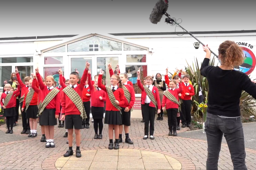 Treloweth Primary School Pupils Singing outside the School, wearing the uniform and Cornish tartan sashes