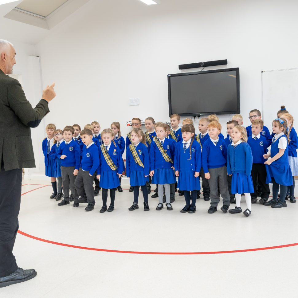 School pupils from Trewirgie Infants, in blue uniform, rehearsing their song performance